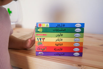 Toddler standing next to a stack of Arabic books